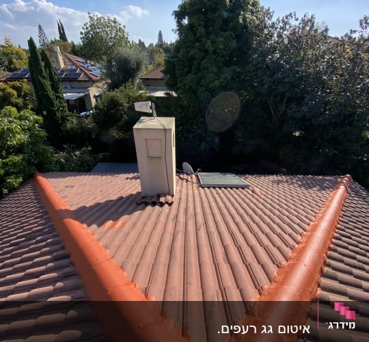 גג רעפים עם צינור אדום ומתקן על הארובה